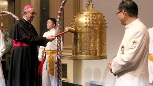 Bishop Camillo Ballin wringing the Bell of World Peace and Love, with Dr. Hong (right).